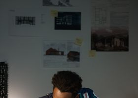 A studio team reviewing a wooden architectural model in warm light